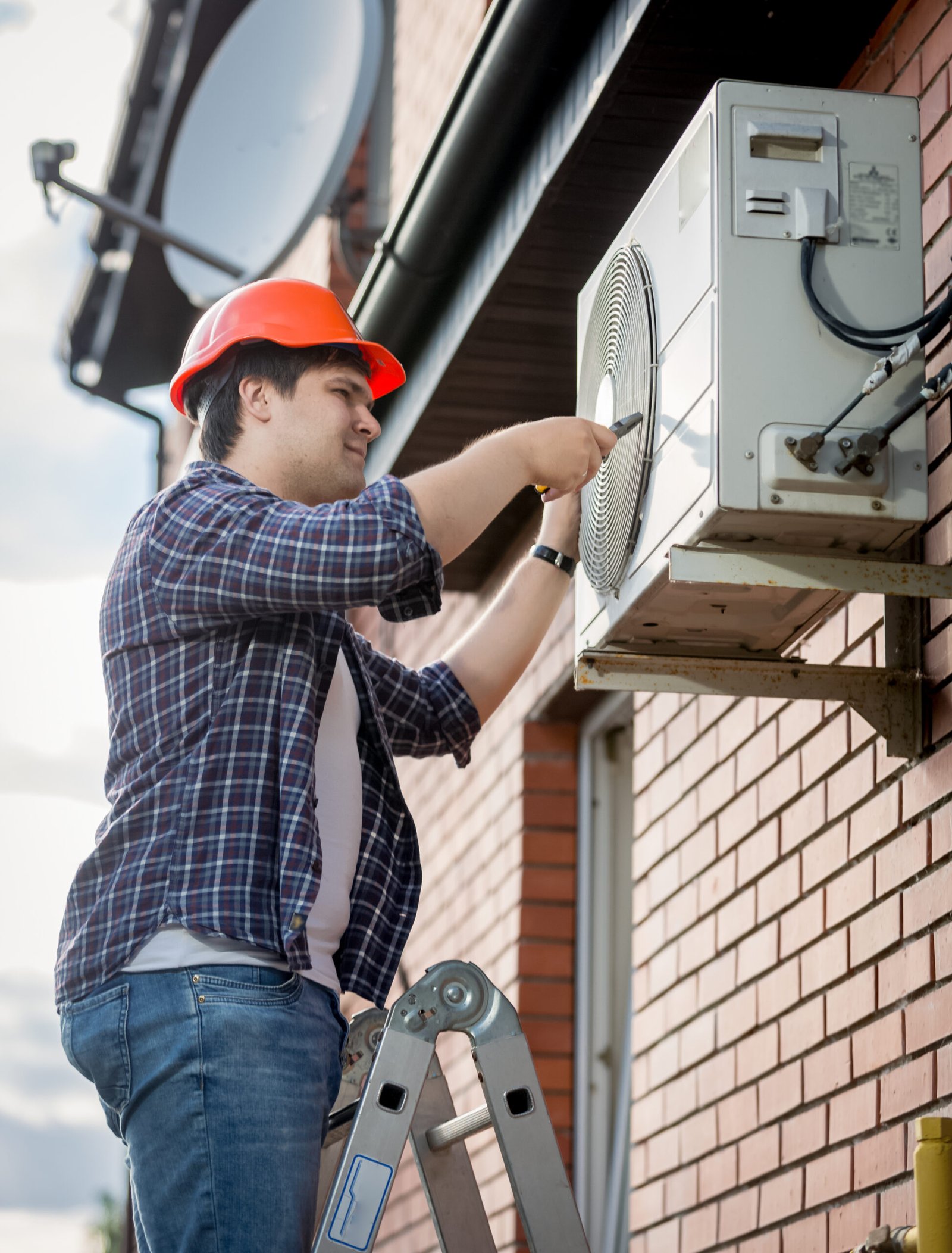 Young male technician repairing outdoor air conditioning system
